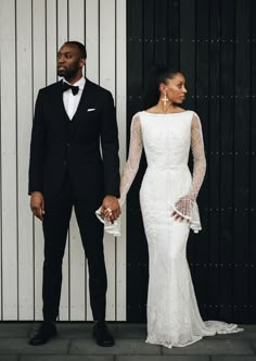 a man in a tuxedo standing next to a woman in a white dress