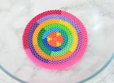 a multicolored object sitting on top of a white counter next to a glass bowl