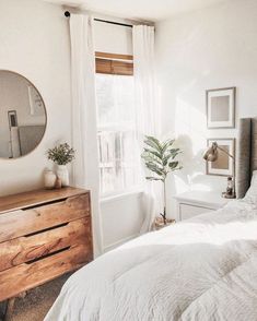 a bedroom with a bed, dresser and mirror on the wall next to a window