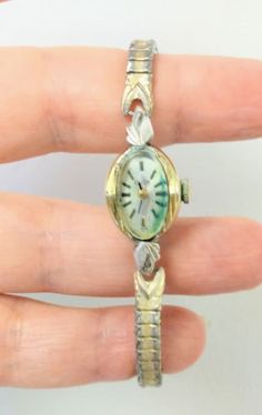 This is a 1950s/1960s Ladies Wind Up Watch by ELGIN. It is gold filled/ chrome/stainless steel, and the watch band is stretchy metal.  The watch cover appears to be glass, but it might be plastic.   Watch needs to be serviced and cleaned as it is NOT RUNNING. It has some verdigris (green rust ) on the dial. Stamped 10 K Rolled Gold Bezel on the back. Please zoom in, and view all photos as they are part of the description. Will fit a wrist from 5.5 to 6 inches comfortably. SOLD AS IS, AS FOUND. N Vintage Handmade Watch For Formal Occasions, Vintage Hallmarked Watches For Evening, Silver Retro Collectible Watch, 1940’s Watches, Antique Costume Jewelry, Antique Yellow Gold Self-winding Watch, Metal Watch, Women Wrist Watch, Wrist Watches