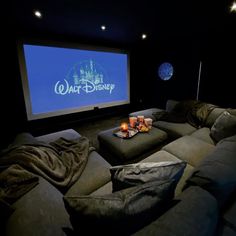 a movie theater with two couches and a projector screen in the middle of it