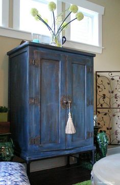 a blue armoire with flowers on top of it