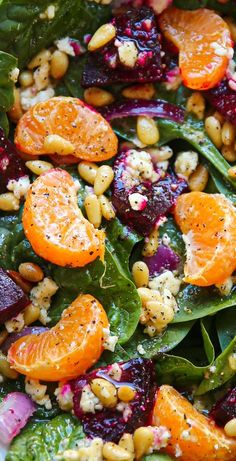 a salad with oranges, spinach and other vegetables