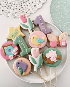 some decorated cookies are on a plate with toothpicks in the shape of letters