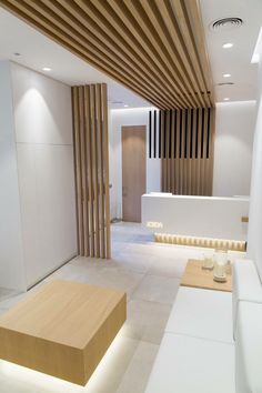 an empty room with white couches and wooden slats on the ceiling, along with coffee tables