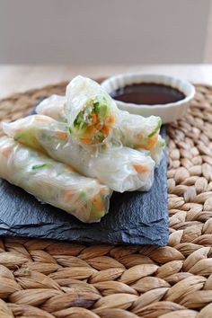 some food that is sitting on top of a mat next to a bowl of dipping sauce