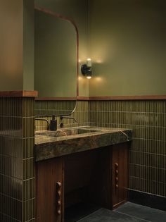 a bathroom with a sink and mirror next to a tiled wall in front of it