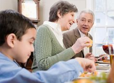 an older man and two young boys eating at a dinner table