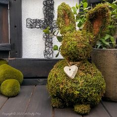 a moss covered bunny sitting next to a potted plant