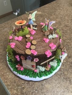 a chocolate cake decorated with flowers and fairy figurines sitting on top of it