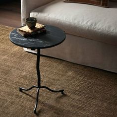 a small table with a book on it in front of a couch and coffee table