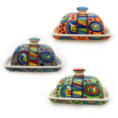 three ceramic dishes with colorful designs on the top and one has a dome shaped lid