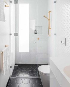 a bathroom with black and white flooring and gold accents on the shower door, toilet and sink