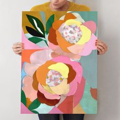 a woman holding up a painting with flowers on it