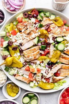 a salad with chicken, cucumbers, tomatoes, olives and feta cheese