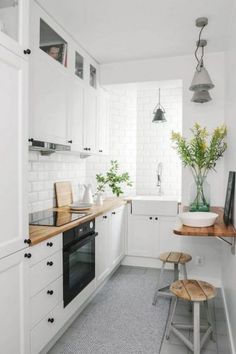 a small kitchen with white cabinets and wooden counter tops, along with two stools