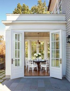 an open patio door leading to a dining room with white chairs and table on it