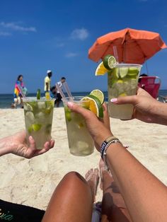 three people toasting on the beach with cocktails