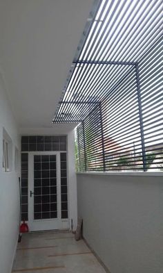 an empty hallway leading to a white door and window with blinds on the outside wall