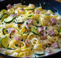 pasta with ham, zucchini and cheese in a skillet on a wooden table