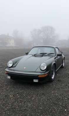 a grey porsche parked on top of a gravel field