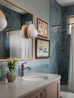 a bathroom with blue tiled walls and a white sink under a mirror next to a bathtub