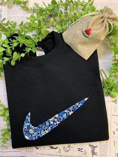 a t - shirt with a blue nike logo on it next to some green plants