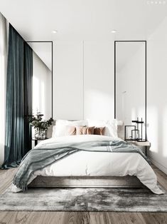 a bedroom with white walls and wood flooring is pictured in this image, there are mirrors on the wall above the bed