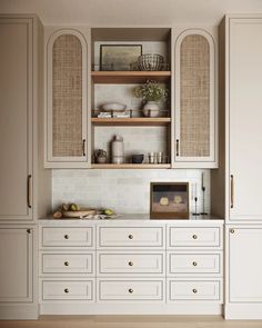 a kitchen with white cupboards and shelves filled with dishes on top of each other