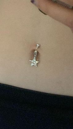 a woman's belly with a small star pendant attached to the side of her stomach