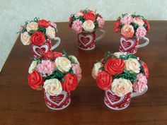 four vases with flowers in them sitting on a wooden table next to each other