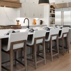 an image of a kitchen setting with white countertops and bar stools in the center