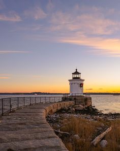 a light house sitting on top of a pier next to the ocean at sunset or dawn