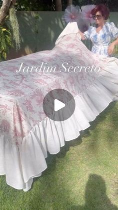 a woman is holding up a pink and white bedspread with ruffles on it