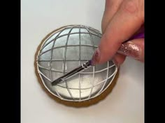 a person is using a pen to draw the globe on top of a round cookie