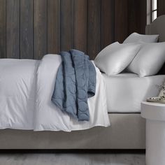 a bed with white sheets and pillows on top of it next to a night stand