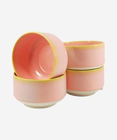 three pink bowls with yellow rims on them