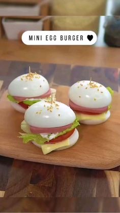 three mini egg burgers sitting on top of a wooden cutting board