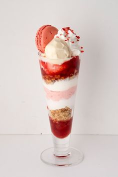 an ice cream sundae with strawberries and whipped cream in a glass on a white background