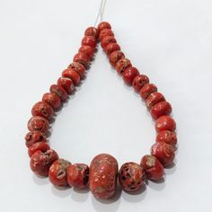 a necklace made with red coral beads on a white surface, including one bead in the shape of an elephant's head