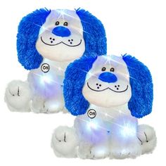 two blue and white stuffed animals sitting next to each other on a white surface with lights