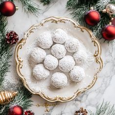 a white plate topped with snow covered donuts next to christmas decorations and baubles