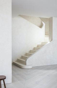 an empty room with stairs leading up to the second floor and a stool in front of it