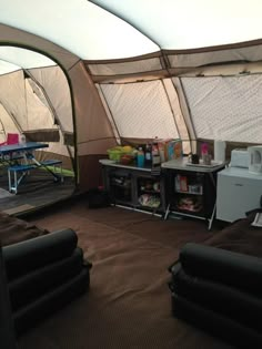 the inside of a tent with couches, tables and refrigerators in front of it