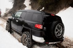 a black truck driving down a snow covered road