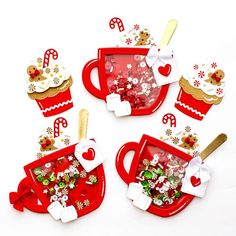 christmas decorations are arranged on red plates and cups with gold spoons, snowflakes, candy canes, and candies