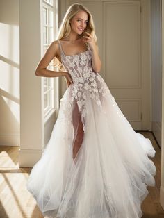 a woman is posing in a white dress with flowers on the skirt and high slit