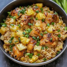 chicken and pineapple stir fry with rice in a bowl on top of a table