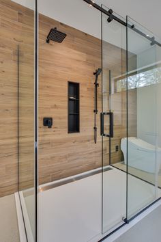 a bathroom with a glass shower door and wooden wall