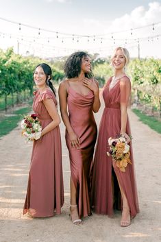 three bridesmaids standing together in front of the vineyard at their winery wedding ceremony